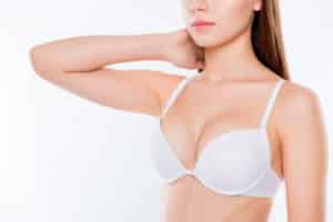Cropped half turned closeup photo womans breast dressed in white bra