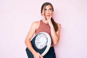Woman holding a scale, thinking about losing weight
