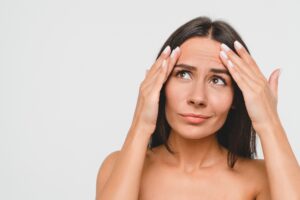 Woman touching her forehead wrinkles and considering a brow lift