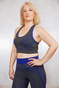 Middle aged woman feels confident in her body and workout attire after losing weight and removing loose skin with body lift surgery