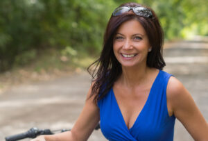 Middle aged woman shows cleavage in her blue top after a breast lift.
